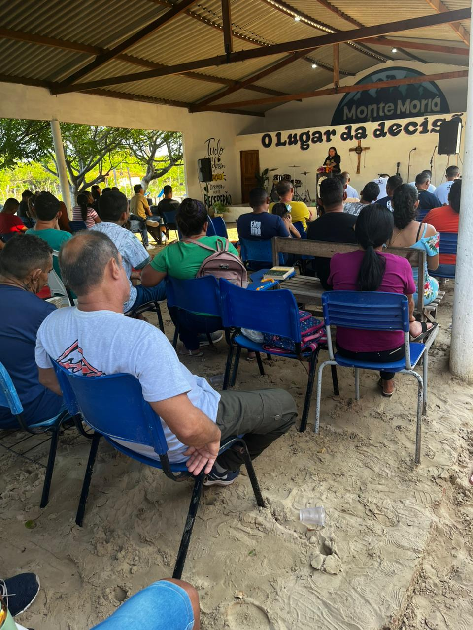 Pessoas reunidas em um culto da Associação Monte Moriá, com o altar visível